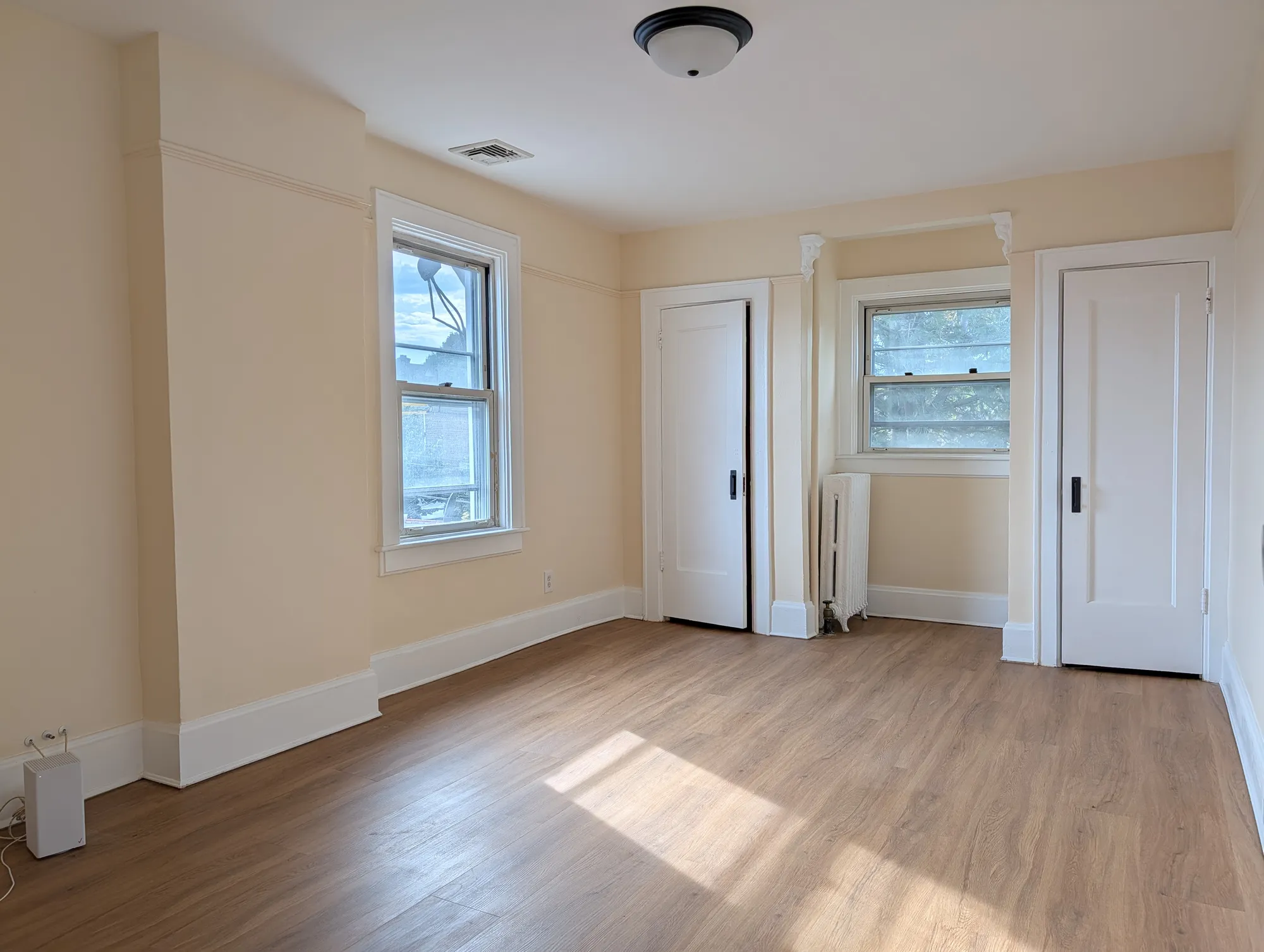 A second-floor bedroom with a window, closets, and sun across the floor