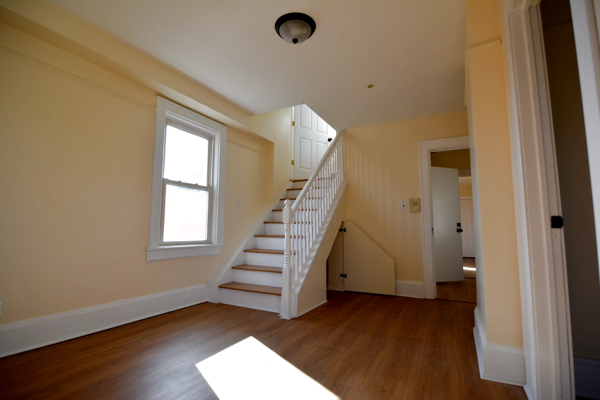 The second-floor landing showing the staircase climbing to the third-floor suite, with a window beside the stair and bonus storage under the steps