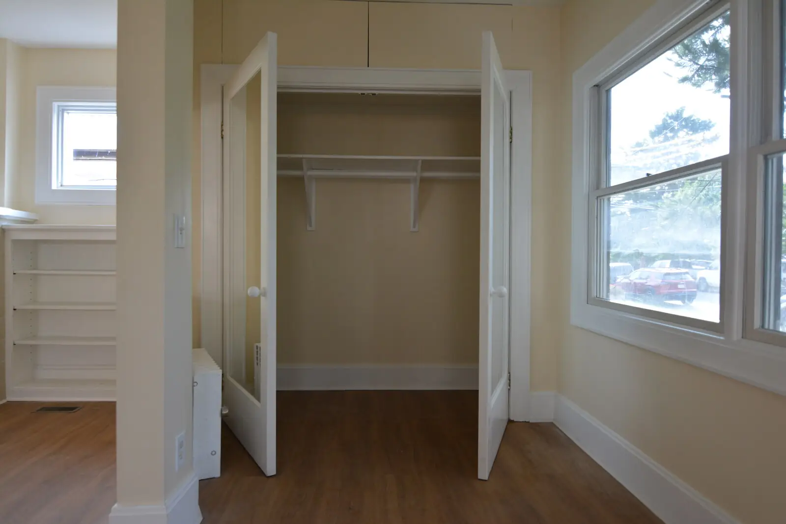 A deep entry closet with double doors open, hanging rod, and a shelf above