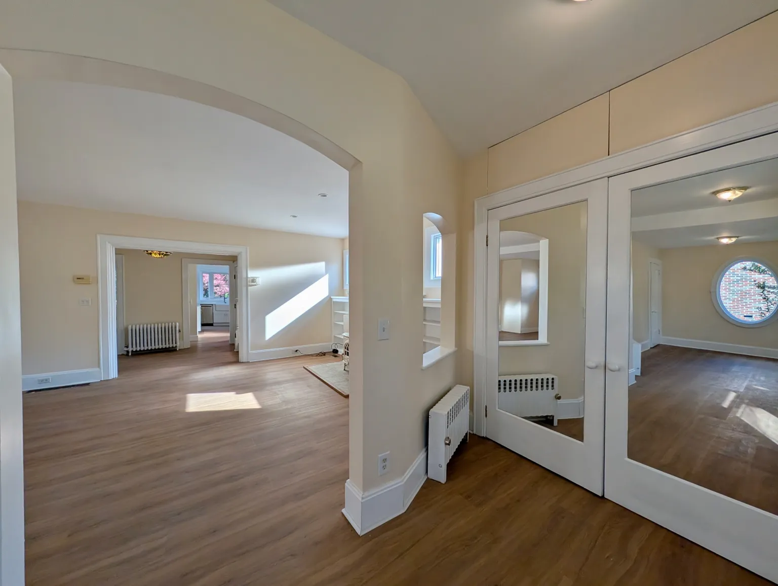The entry looking through an archway and a line of rooms to a bright window at the back of the house