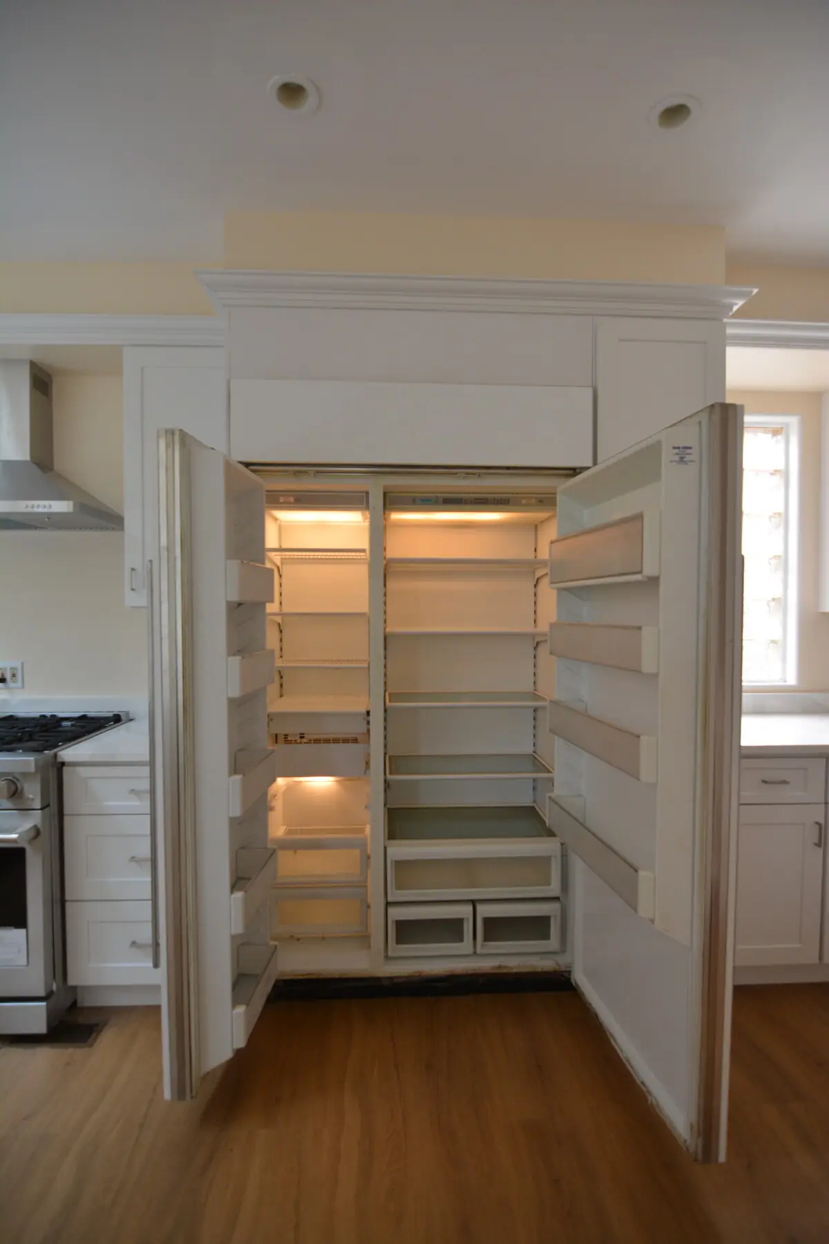 The panel-front built-in refrigerator with both doors open showing the side-by-side fridge and freezer