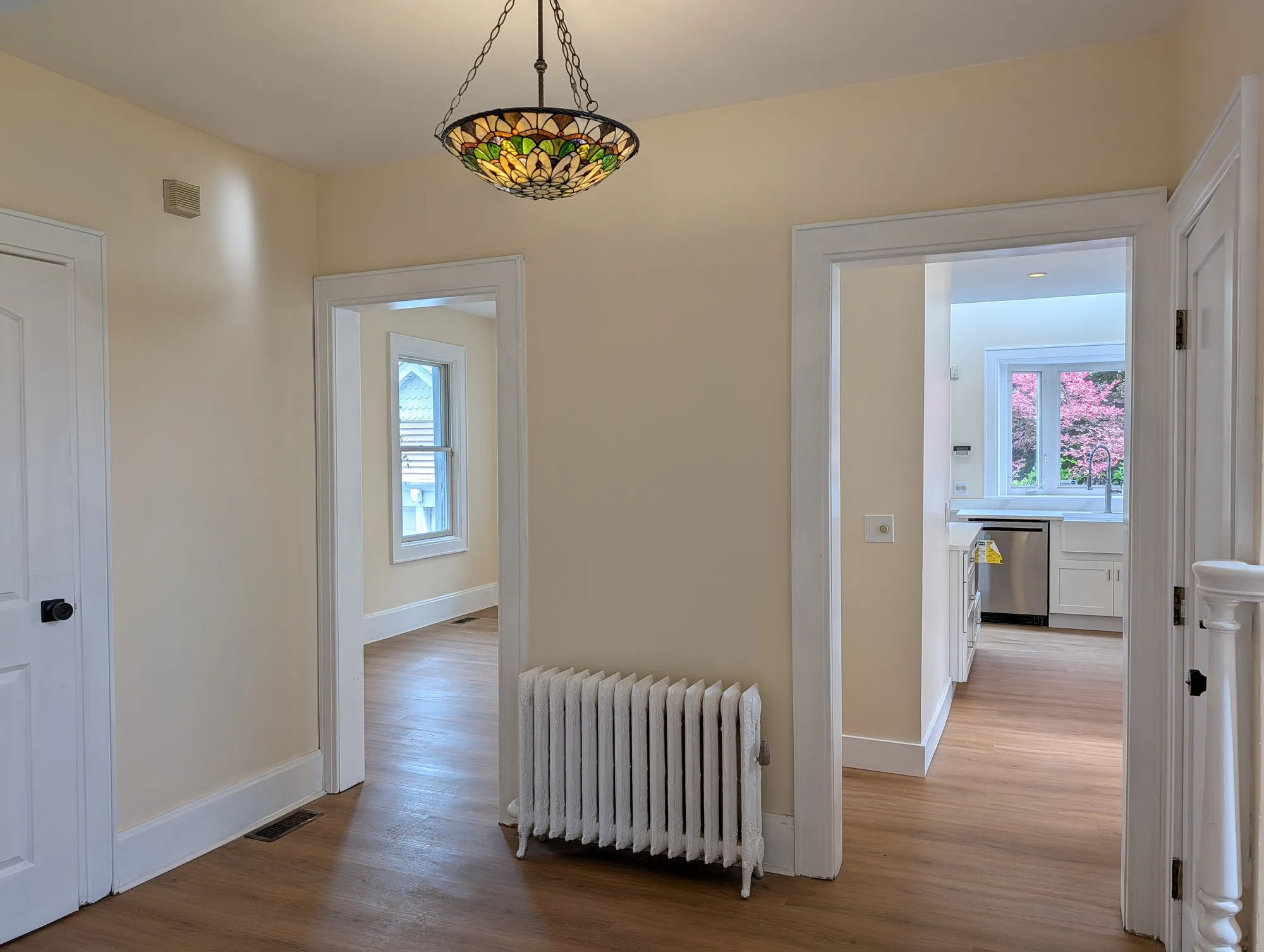 View from the living room toward the kitchen, with a stained-glass pendant above and an antique cast-iron radiator alongside