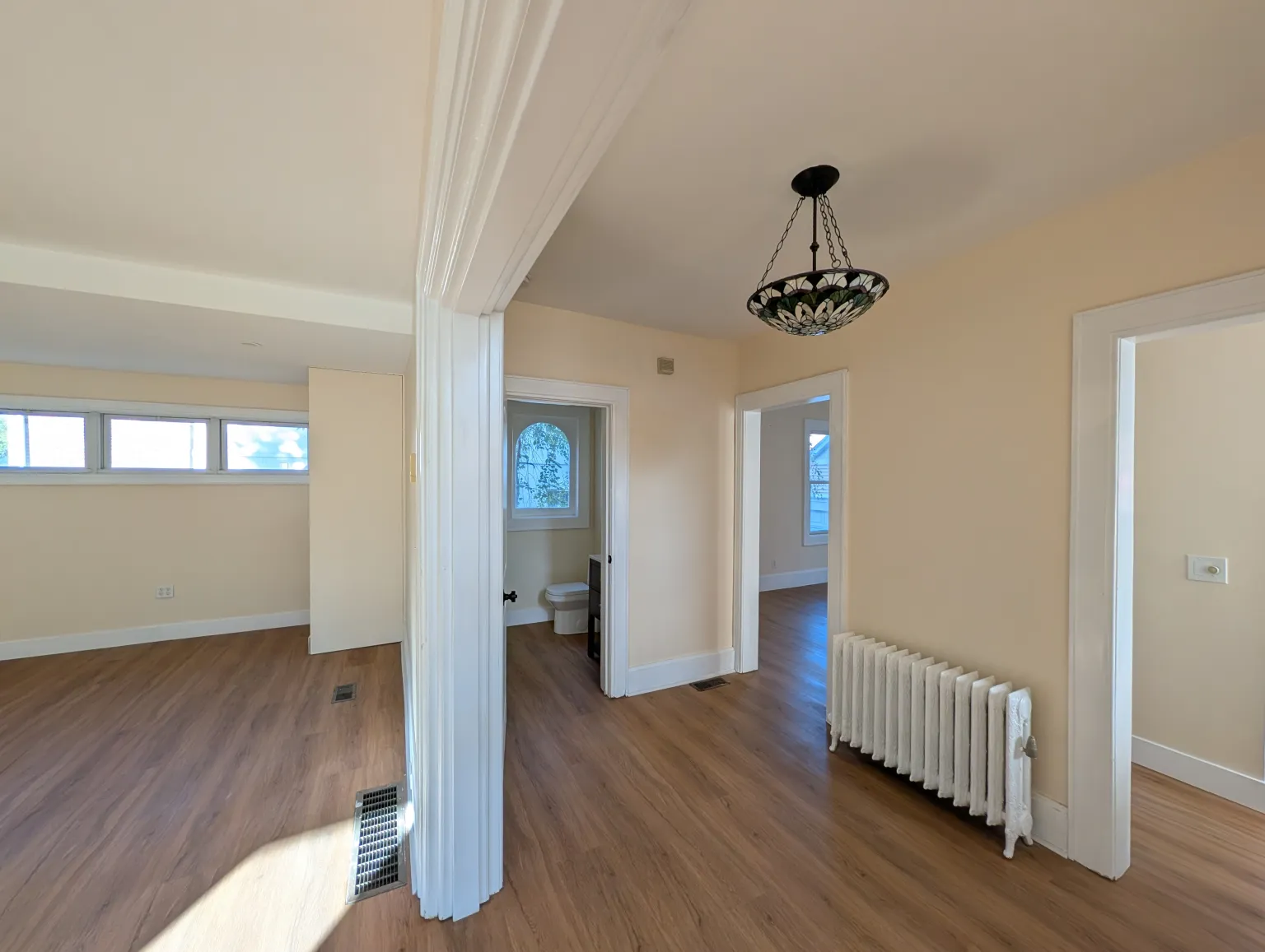 The main-floor living room under a hanging fixture, with a band of windows along one wall