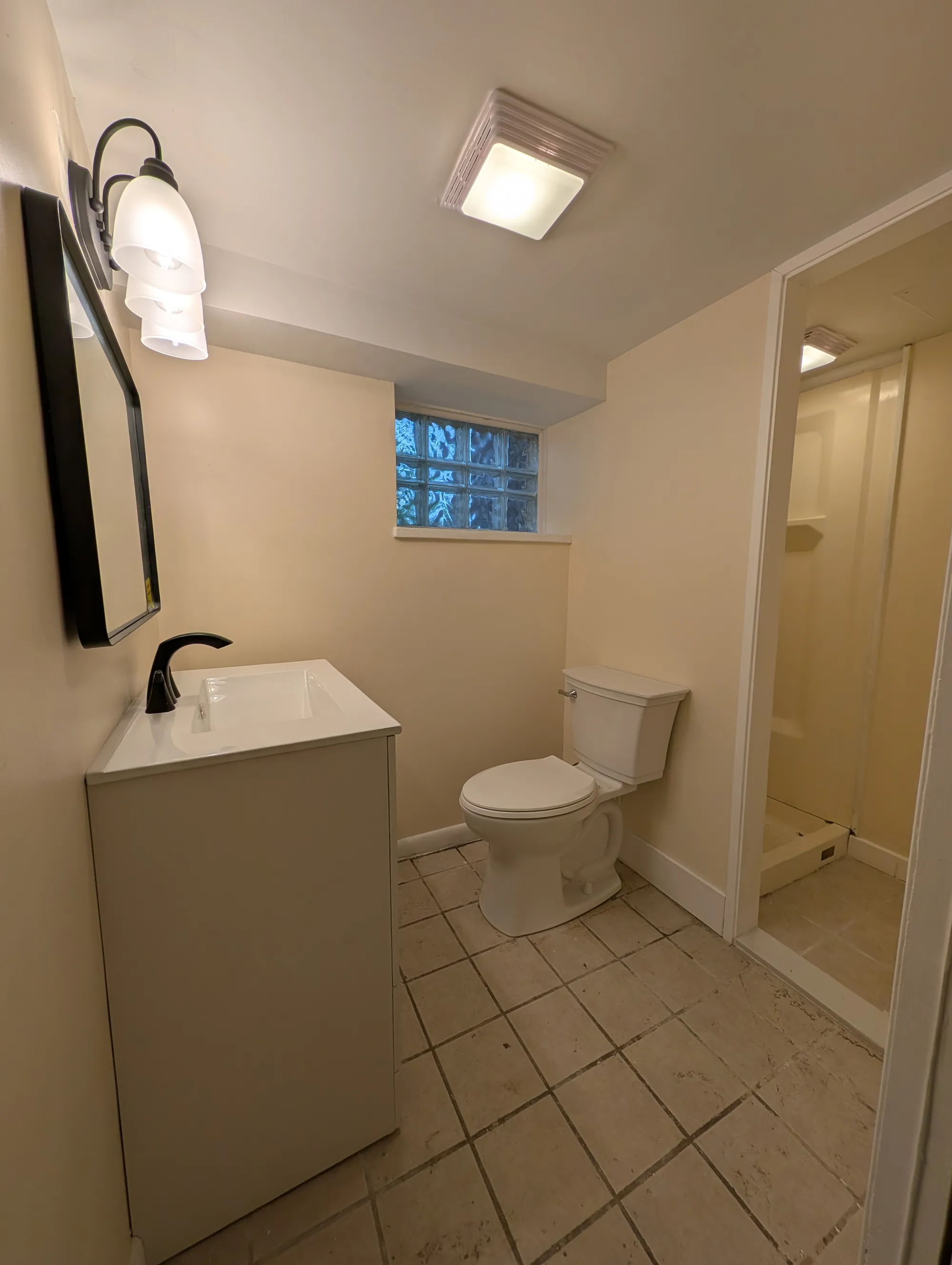 Lower-level full bathroom with vanity and glass-block window