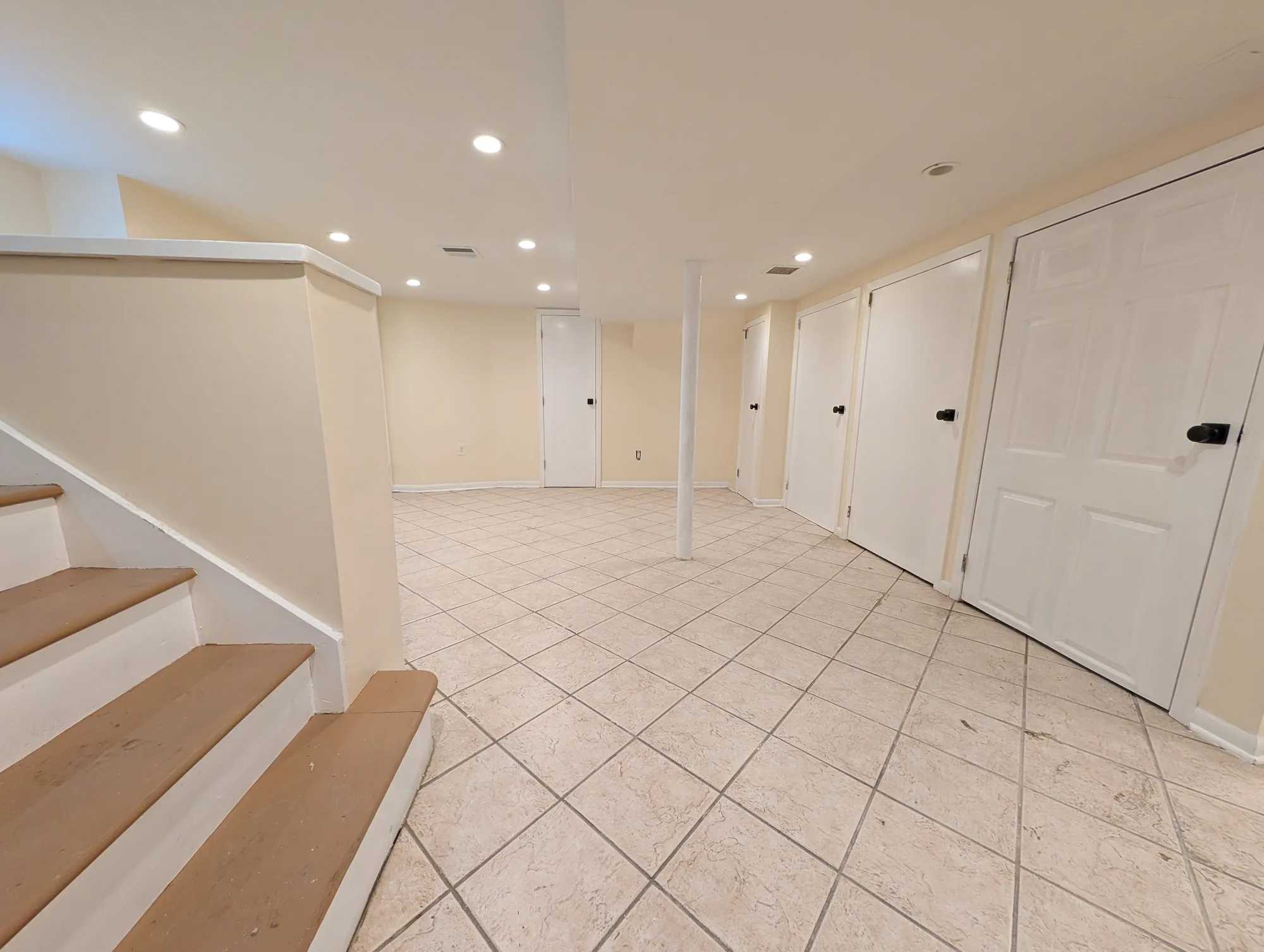 Finished lower-level rec room with recessed lighting and tile floor