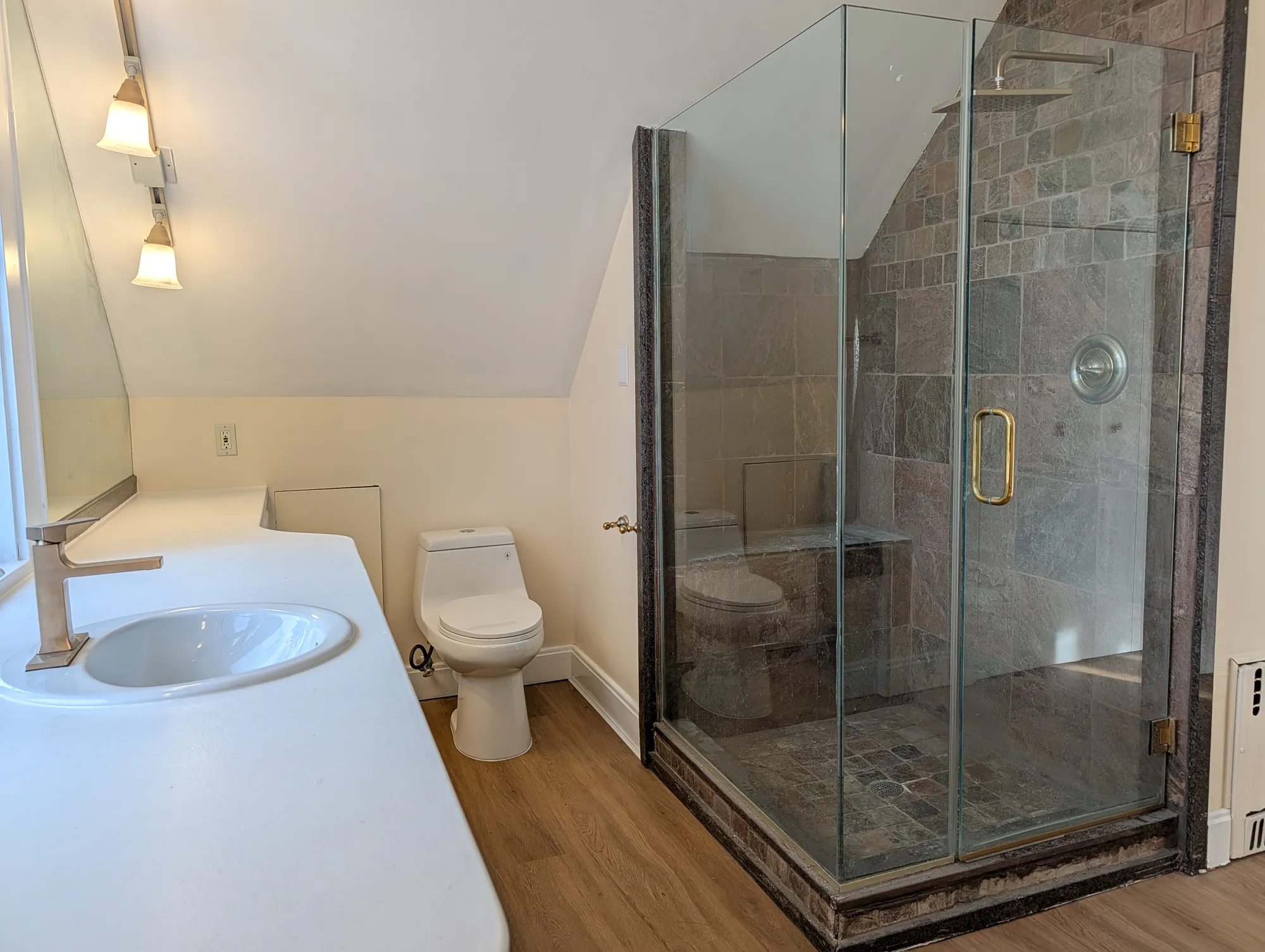 Suite bath with a frameless glass shower and brass fixtures