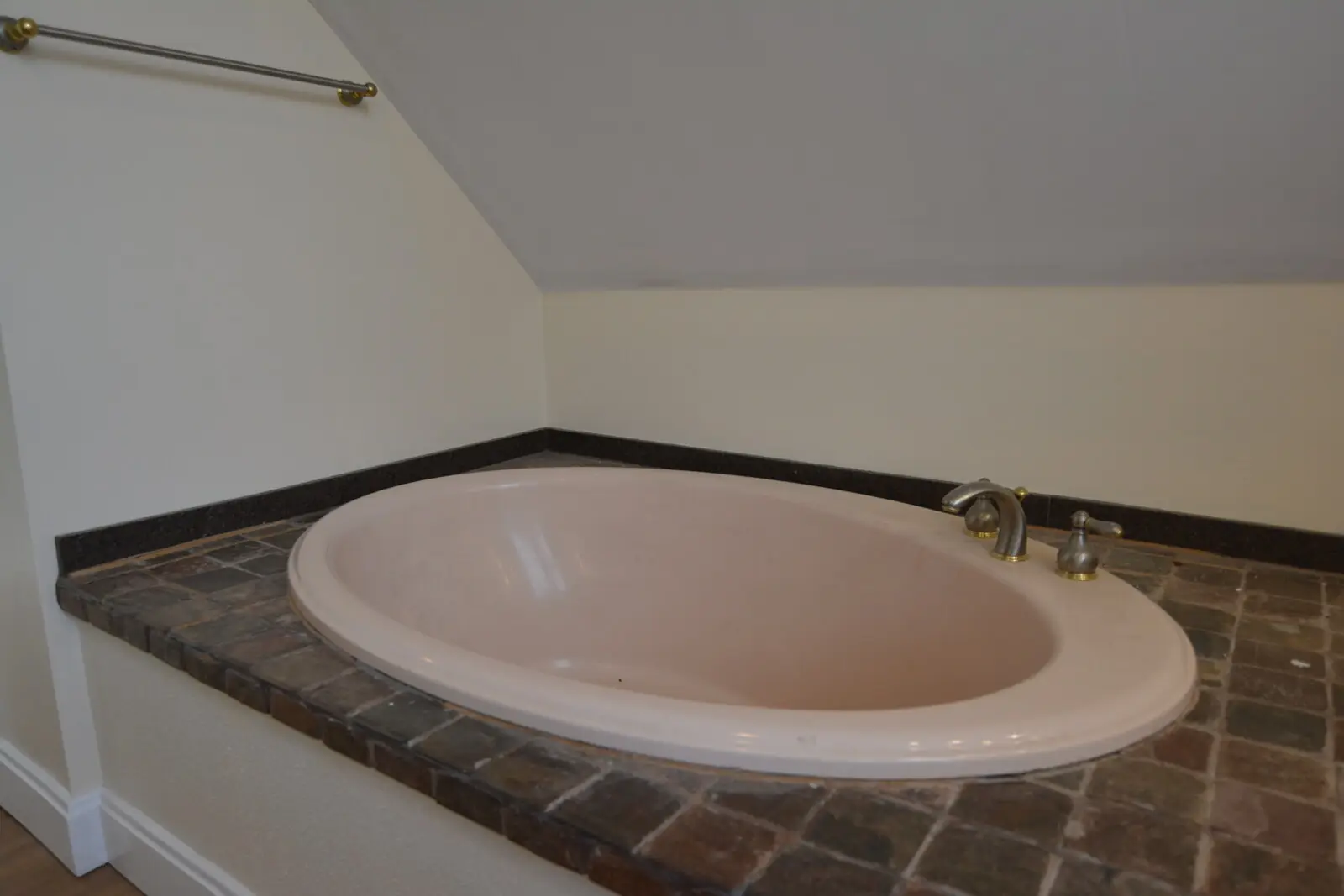 Oval soaking tub set into a tiled surround under the suite eaves