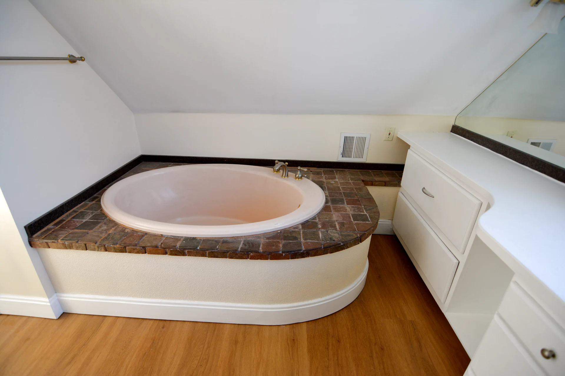 The soaking tub from the corner, built into the eave with vanity drawers alongside