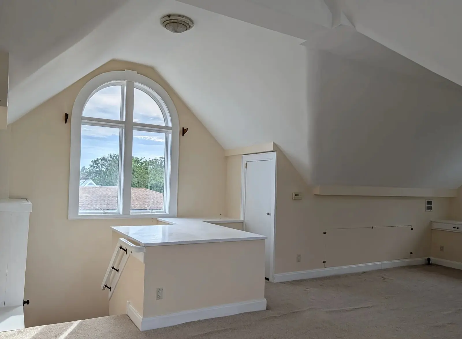 The west end of the suite, arched window over the rooftops, internal stair landing alongside