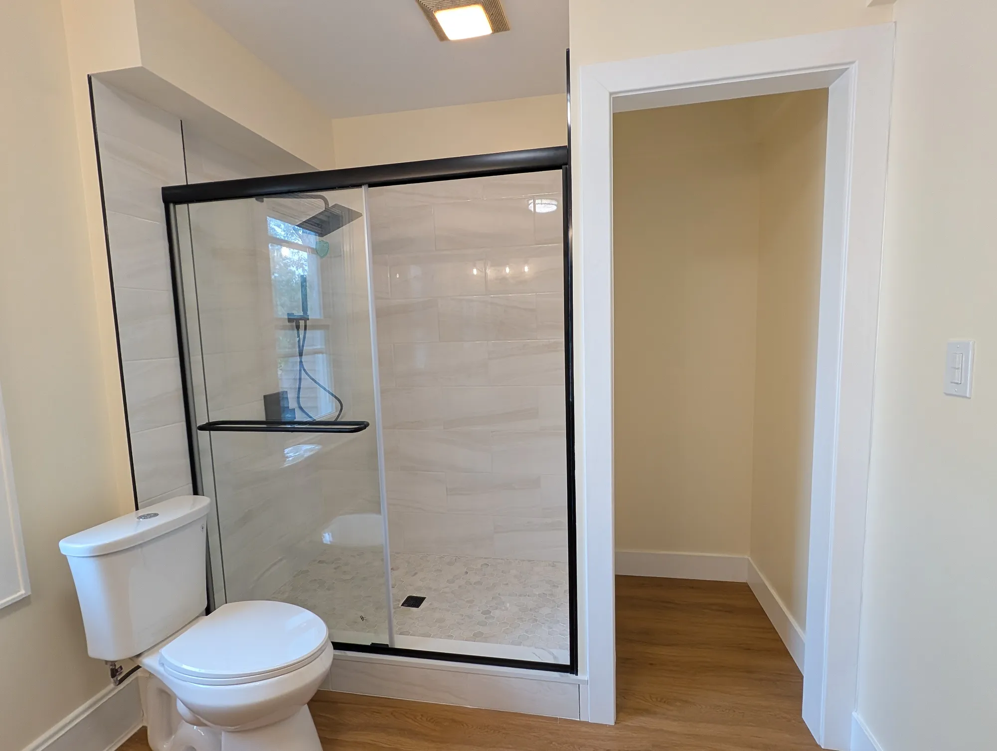 The second-floor bath from the side, toilet and shower along one wall, with a recessed alcove for a linen closet beside the shower